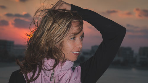 Smiling woman posing against sky during sunset