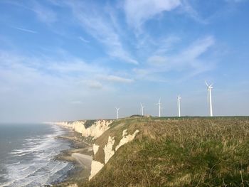 Scenic view of sea and cliff with wind turbines 