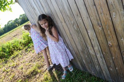 Sisters holding hands while standing against fence