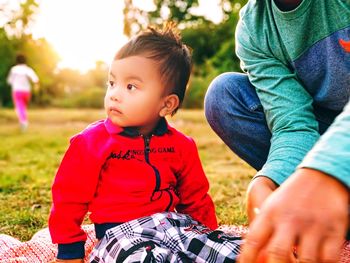 Midsection of father with son sitting on field at park