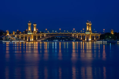 Illuminated bridge over river against clear blue sky