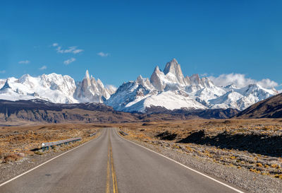 Road leading towards snowcapped mountains against sky