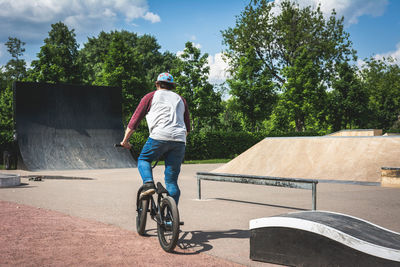 Rear view of man riding bicycle on road