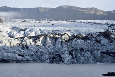 Scenic view of sea by mountains coverd in glacier ice against sky