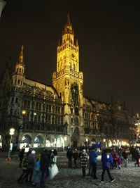 People on illuminated building in city at night