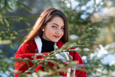 A young, beautiful brunette with a red plaid on her shoulder and a cup of tea in her hands