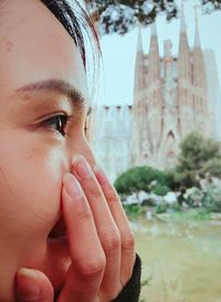 Close-up of woman covering mouth with hand against church