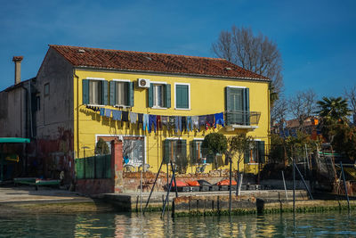 Buildings by river against sky