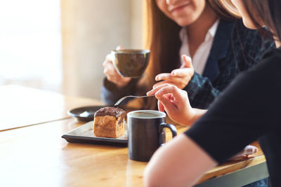 Midsection of woman holding coffee cup on table