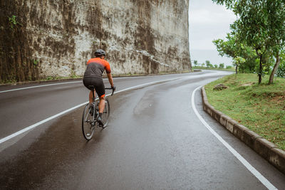 Rear view of man riding bicycle on road