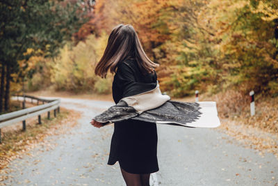 Rear view of woman standing against trees