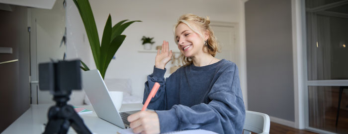 Young woman using mobile phone while sitting on sofa at home