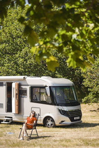 Mature woman relaxing on chair against motor home at trailer park