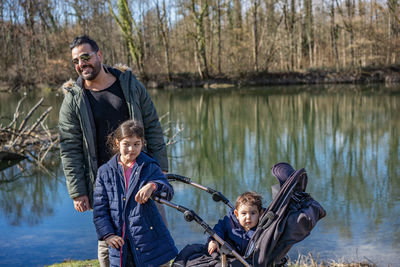 Portrait of smiling young woman standing by lake