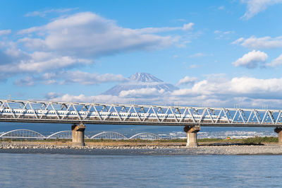 Bridge over sea against cloudy sky