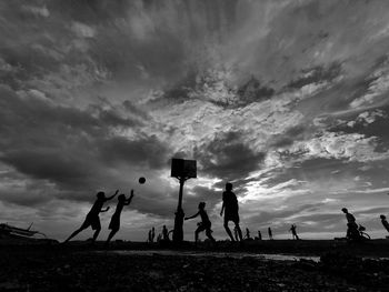 People on beach against sky during sunset