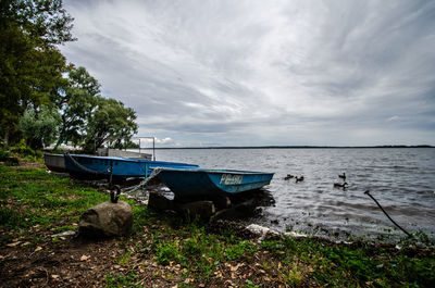 Boat moored on shore against sky