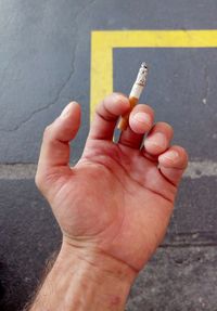 Close-up of hand holding cigarette