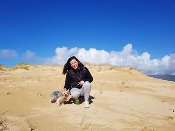 Full length of woman with dog on beach against sky