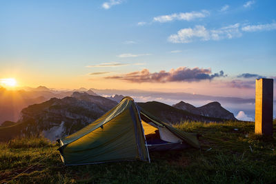 Tent on field against sky during sunset