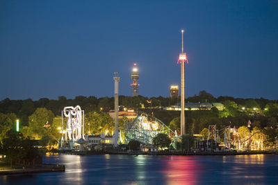 Illuminated grona lund by saltsjon against clear blue sky