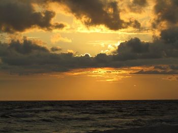 Scenic view of sea against dramatic sky during sunset