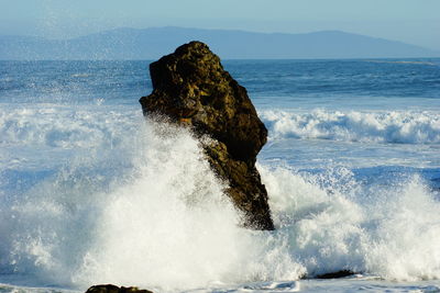 Waves crashing on rock formation in sea