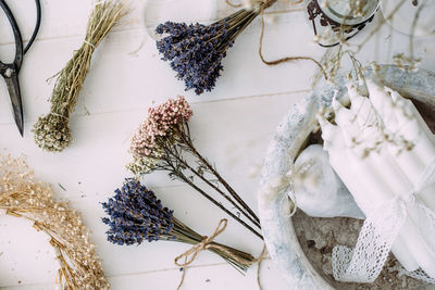 Dry compositions and bouquets of flowers and plants for the interior lie on a white wooden table.