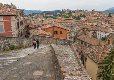 Rear view of people walking on street amidst buildings in town