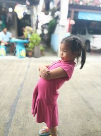 Cute girl with arms crossed standing on footpath