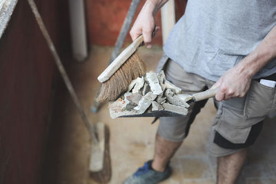 Caucasian male builder sweeps construction debris.