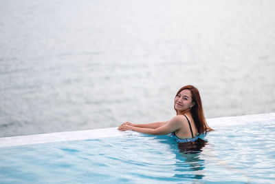 Smiling woman swimming in infinity pool