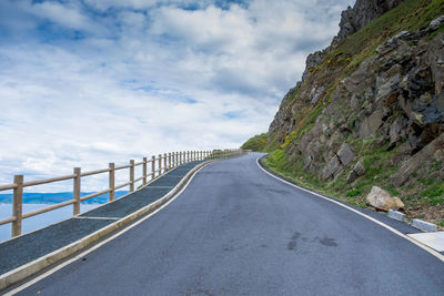 Road by railing against sky