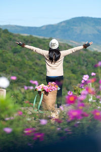 Rear view of woman standing by flowering plants