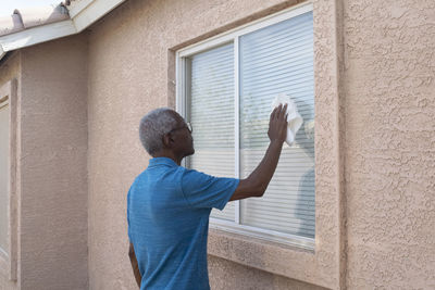 Man cleaning window of house