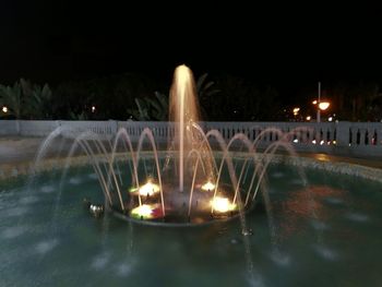 Illuminated fountain against sky at night