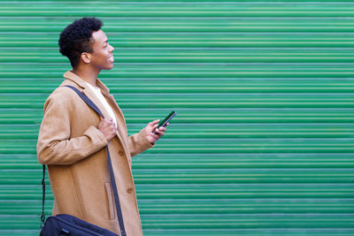 Side view of a young man using smart phone