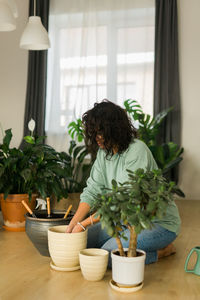 Portrait of young woman with potted plant at home