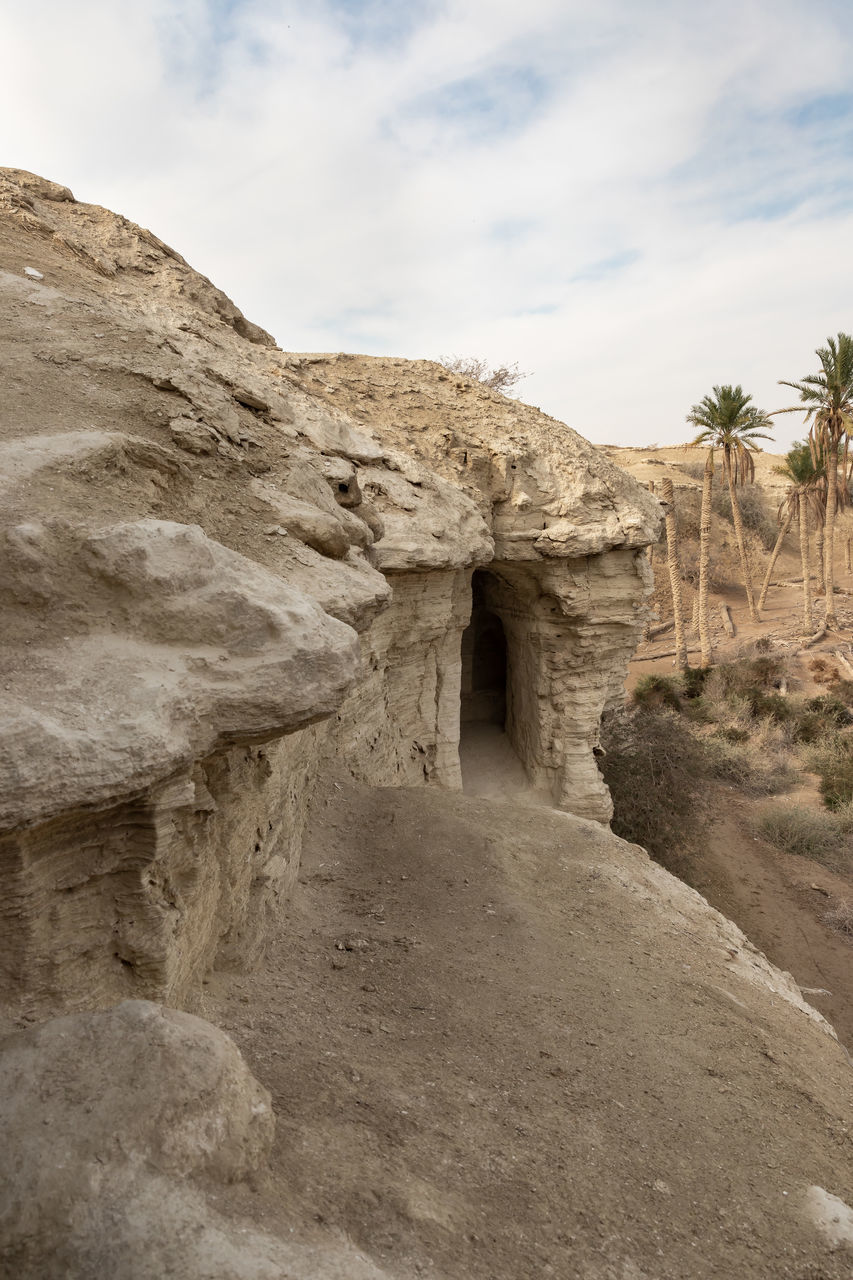 rock, sky, cloud, ancient history, architecture, history, nature, the past, ruins, ancient, travel destinations, land, landscape, wadi, geology, scenics - nature, travel, desert, environment, no people, arch, non-urban scene, built structure, old ruin, temple, rock formation, outdoors, terrain, day, beauty in nature, climate, plant, mountain, sand, extreme terrain, tourism, tree, arid climate, ancient civilization, tranquility, wall, stone material, cave, physical geography