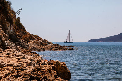 Scenic view of sea against clear sky,  a sailboat on the horizon.