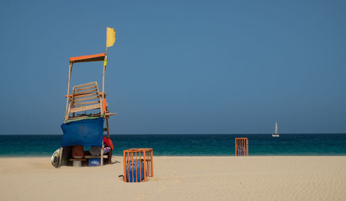Lifeguard hut on beach against clear blue sky