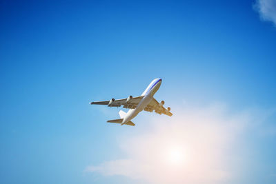 Low angle view of airplane flying against blue sky