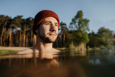 Portrait of young man soaks in the winter lake at morning. male person taking care of his heath