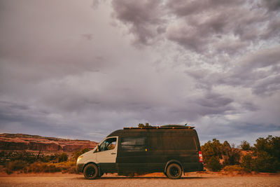 Camper van off side of dirt road during golden sunset in moab, utah.
