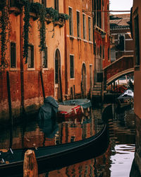 Boats moored in canal by buildings in city