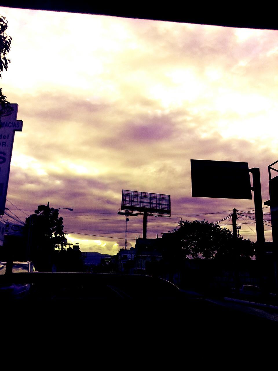 sunset, sky, silhouette, cloud - sky, building exterior, built structure, architecture, communication, street light, city, tree, text, transportation, western script, low angle view, dusk, road sign, car, cloud, outdoors