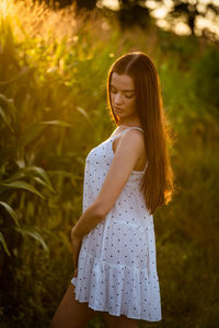 Young woman standing against plants