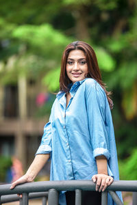 Portrait of young woman standing against trees