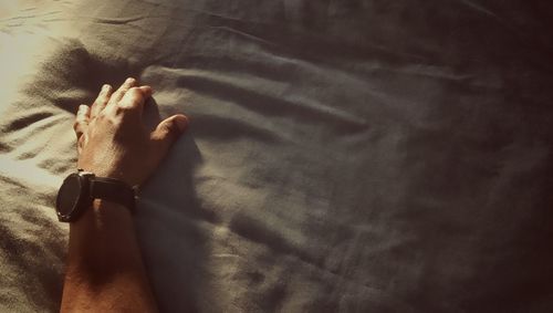 High angle view of person hand on bed