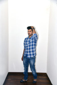 Full length of young man standing against wall